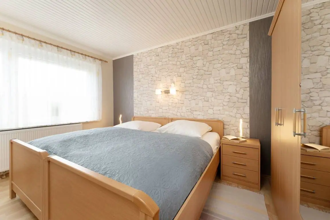 Schlafzimmer mit Doppelbett, blauer Tagesdecke und Fenster